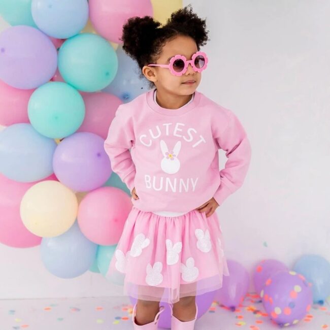 little girl in pink bunny sweatshirt with pastel balloons